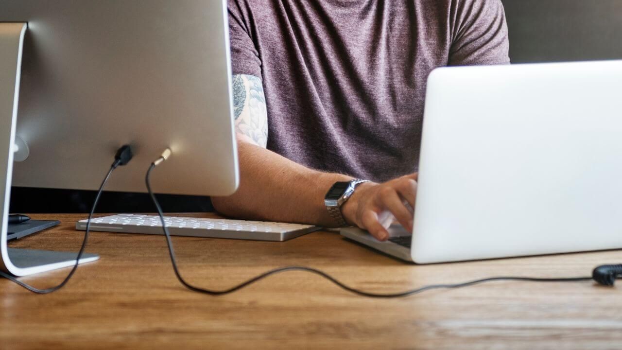 Man with a laptop connected to a wide monitor
