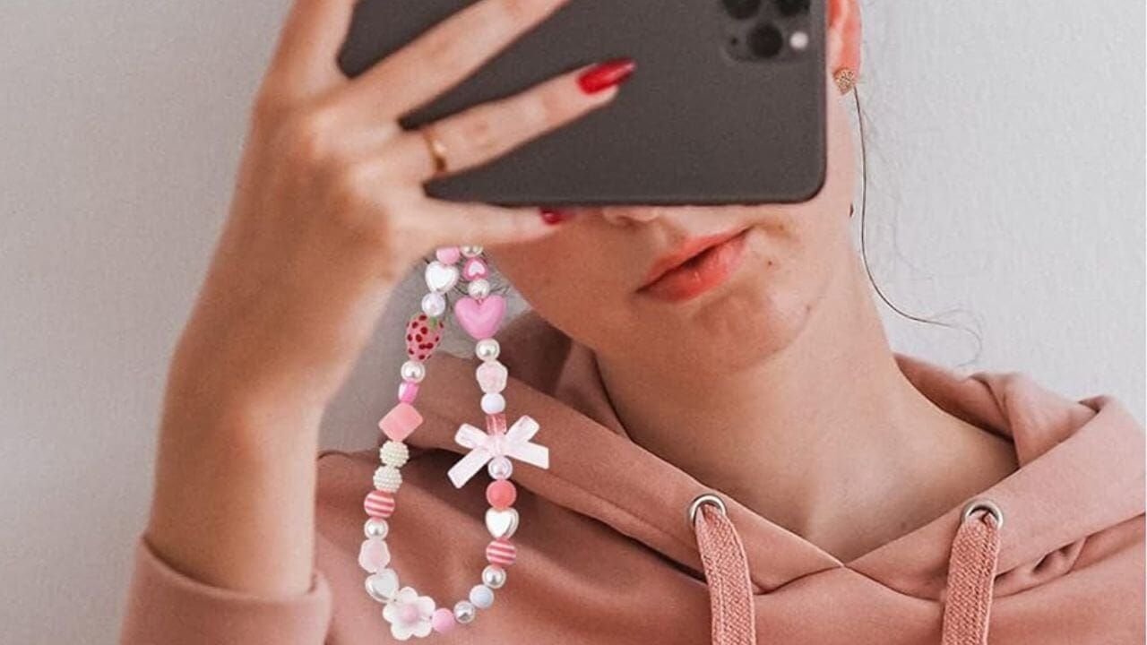 Woman viewing her phone that has a phone charm attached