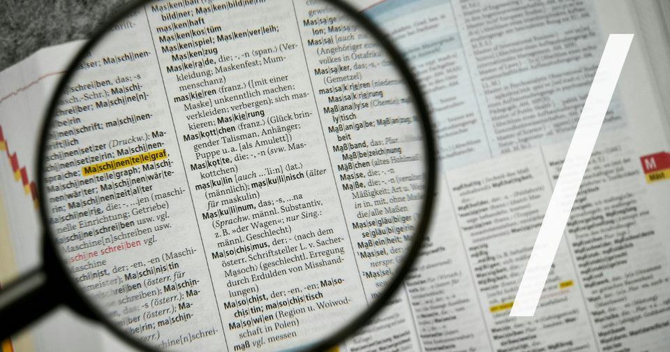 Foto: Magnifying glass focuses on a dictionary page. Unsplash/Joachim Schnürle
