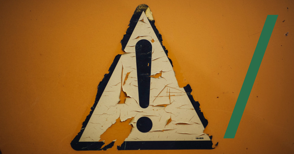 Foto: A triangle shaped sign on a yellow wall. Markus Spiske/Unsplash