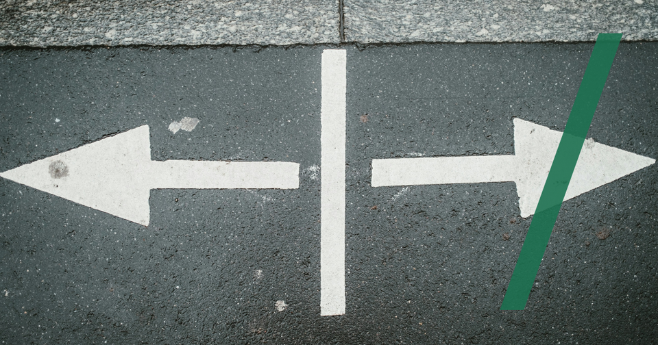 Foto: Two white arrows pointing in opposite directions on asphalt. Claudio Schwarz/Unsplash