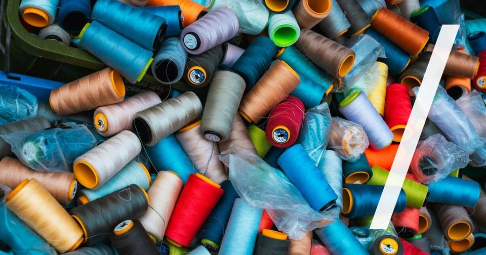 Foto: Bunte Garnrollen dicht an dicht in einem großen Haufen. Thilina Alagiyawanna/Unsplash
