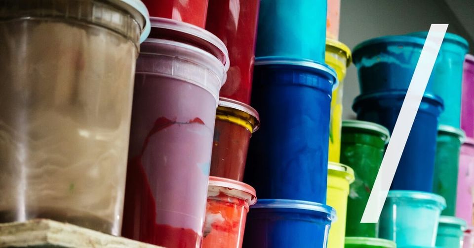 Foto: Farbeimer in kräftigen Farben stapelweise in Werkstattregalen. Anthony Roberts/Unsplash