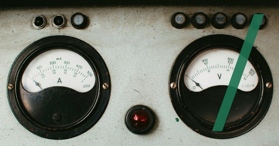 Foto: Zwei alte analoge Messinstrumente, ein Ampere- und ein Voltmeter, auf einer verwitterten Schalttafel. Markus Spiske/Unsplash