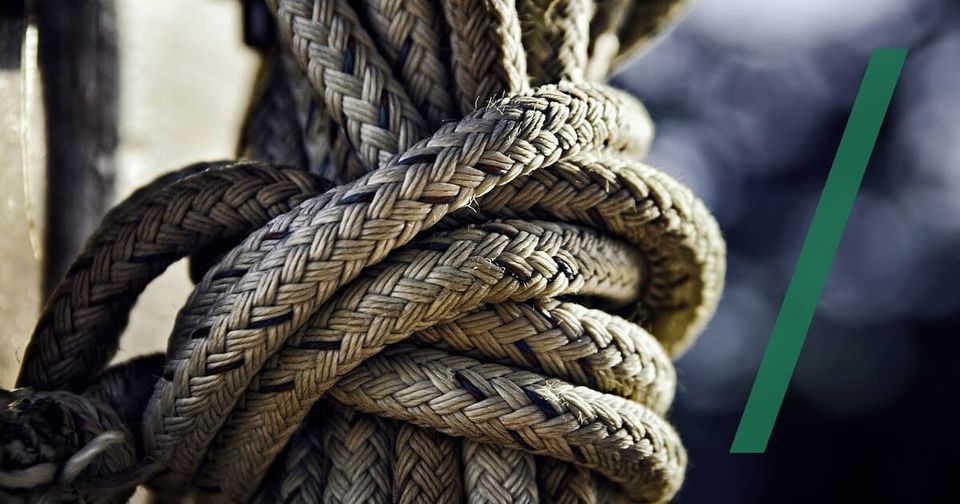 Foto: Ein dicker, geflochtener Seilknoten vor dunklem, unscharfem Hintergrund. Robert Zunikoff/Unsplash