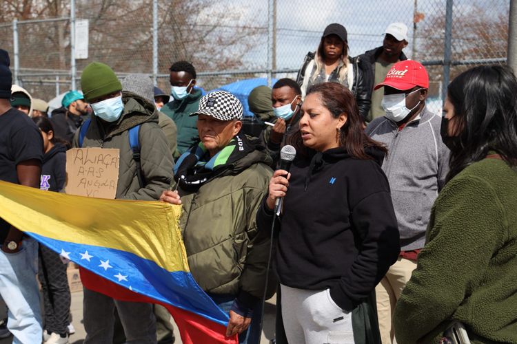 A woman speaks into a microphone, with others standing beside and behind her
