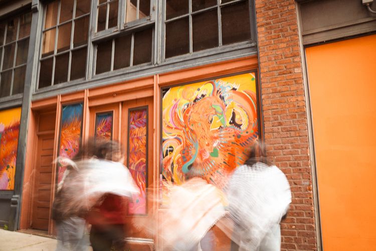 Double exposure photo of blurry people wearing kuffiyehs looking at a building with murals