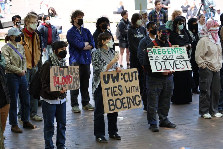 People hold protest signs while gathering on campus