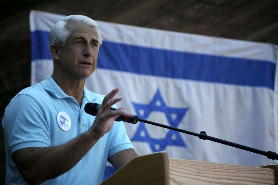 Dave Reichert speaking with Israeli flag in background