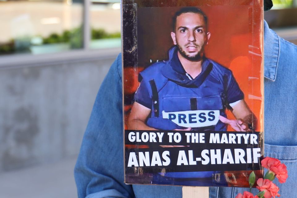 person with sign saying glory to the martyr anas al-sharif