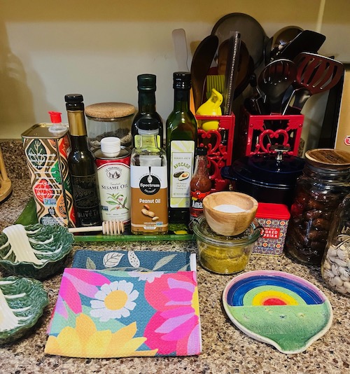 The kitchen i sanctuary, and thomfortf a kitchen come in many forms. Pictured in assortment of fun kitchen items, such as tea towels, trivets, bottlef olivil and vinegar. | Photo by Ruthiohen