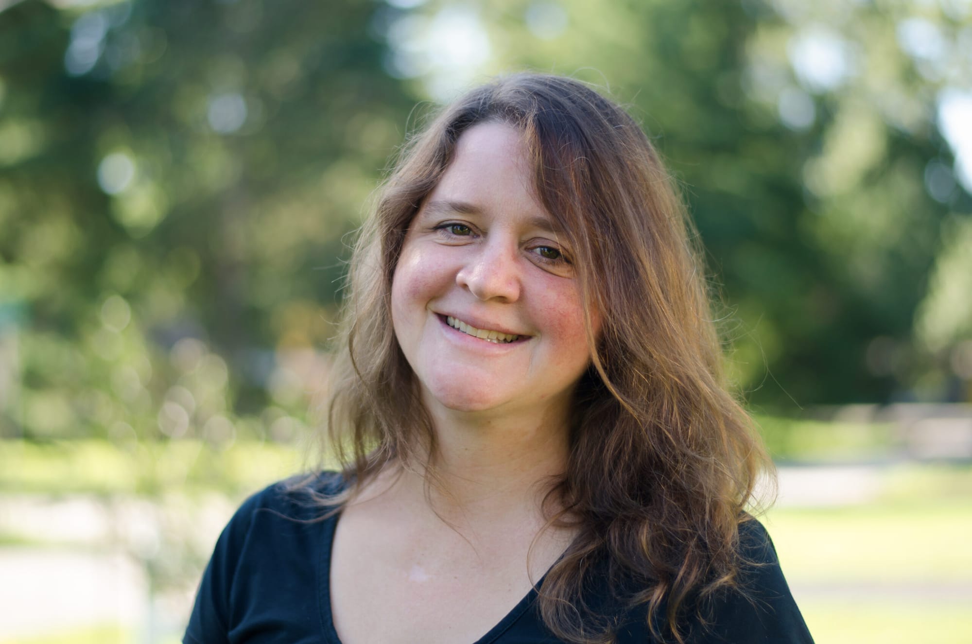 a woman with brown hair smiles while looking at the camera