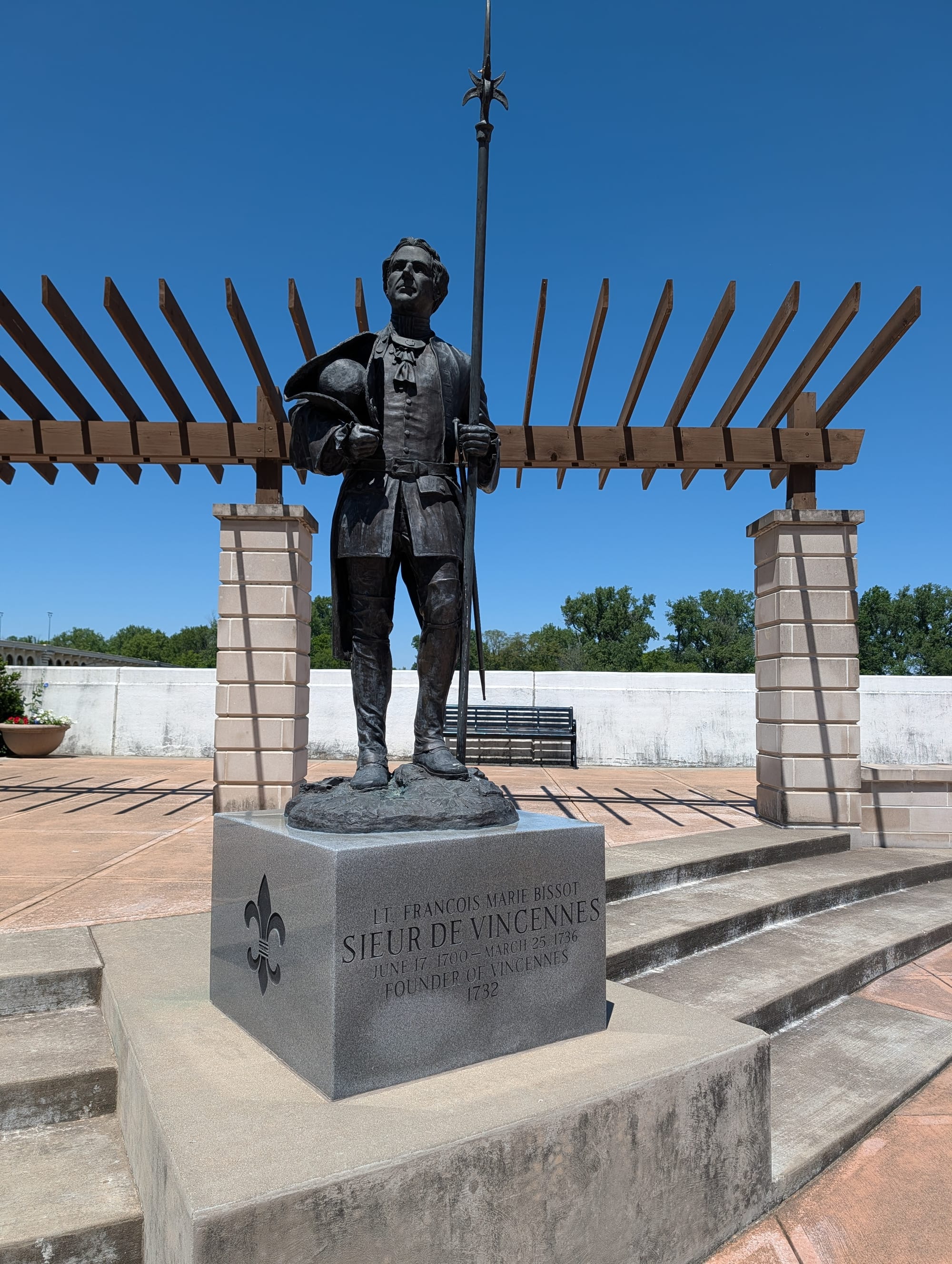 a metal statue of an 18th century man holding a tricorn hat and a large pike