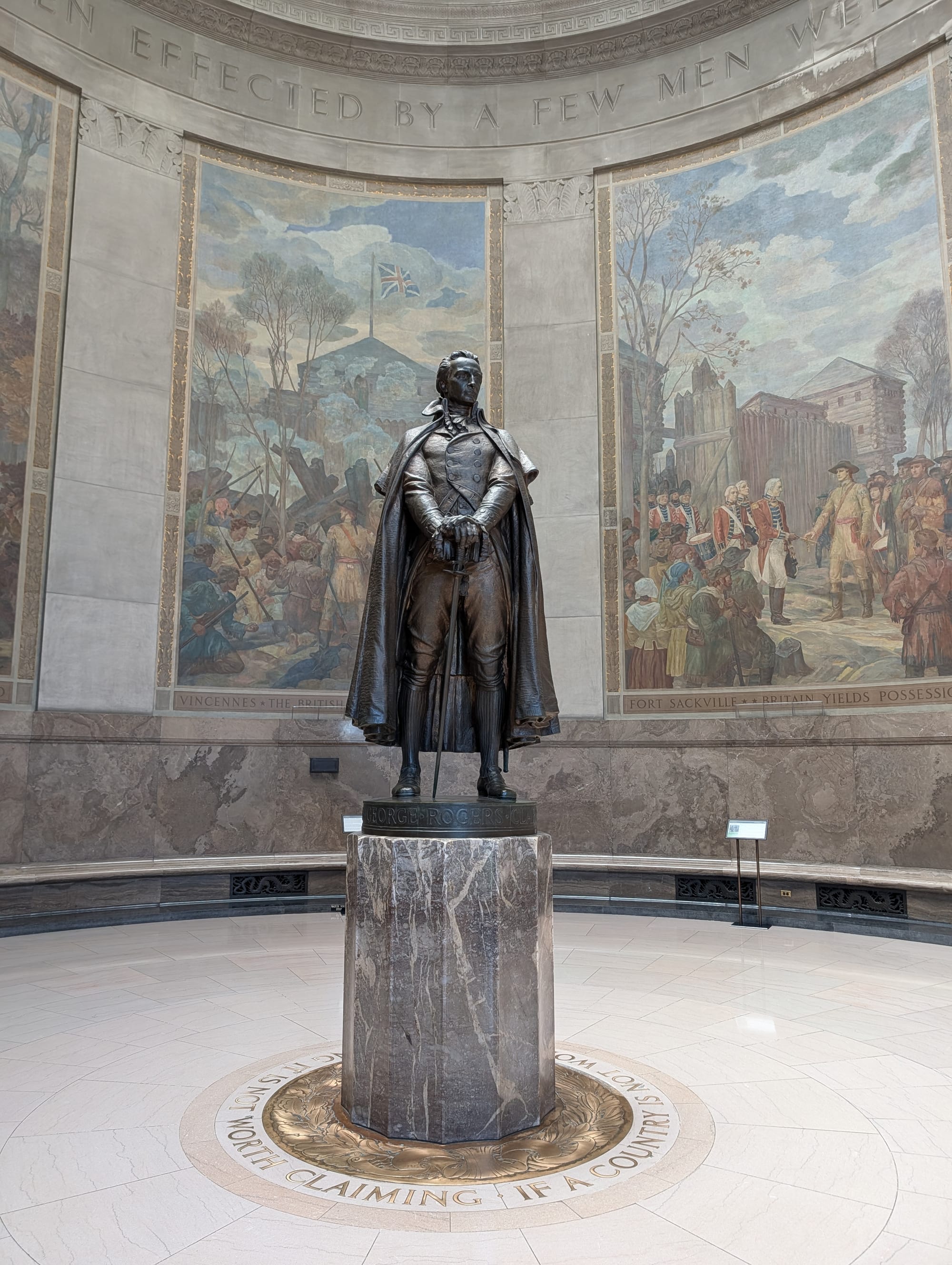 an imperious bronze statue inside a round room, surrounded by tall murals