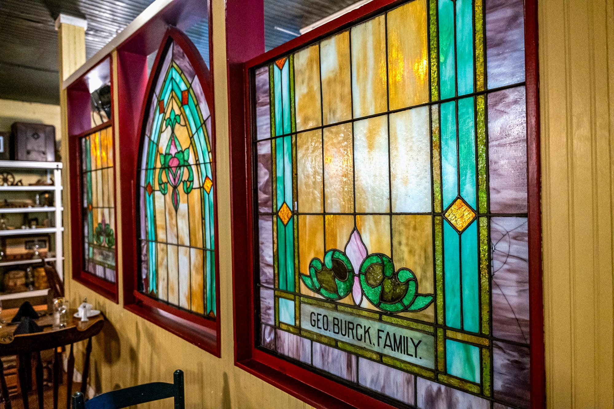 three stained glass windows as ornate decoration inside a rustic restaurant