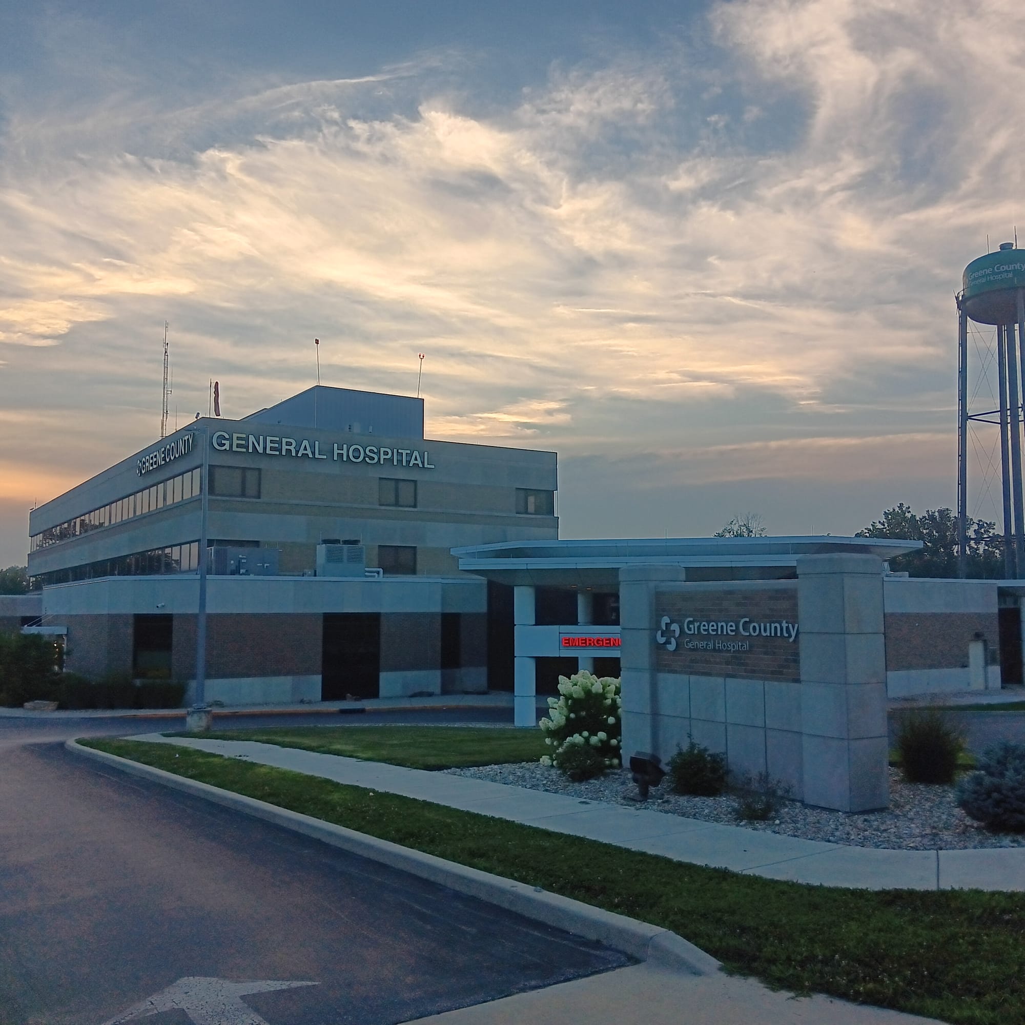 a rectangular hospital building with its own water tower contrast against a cloudy evening sky