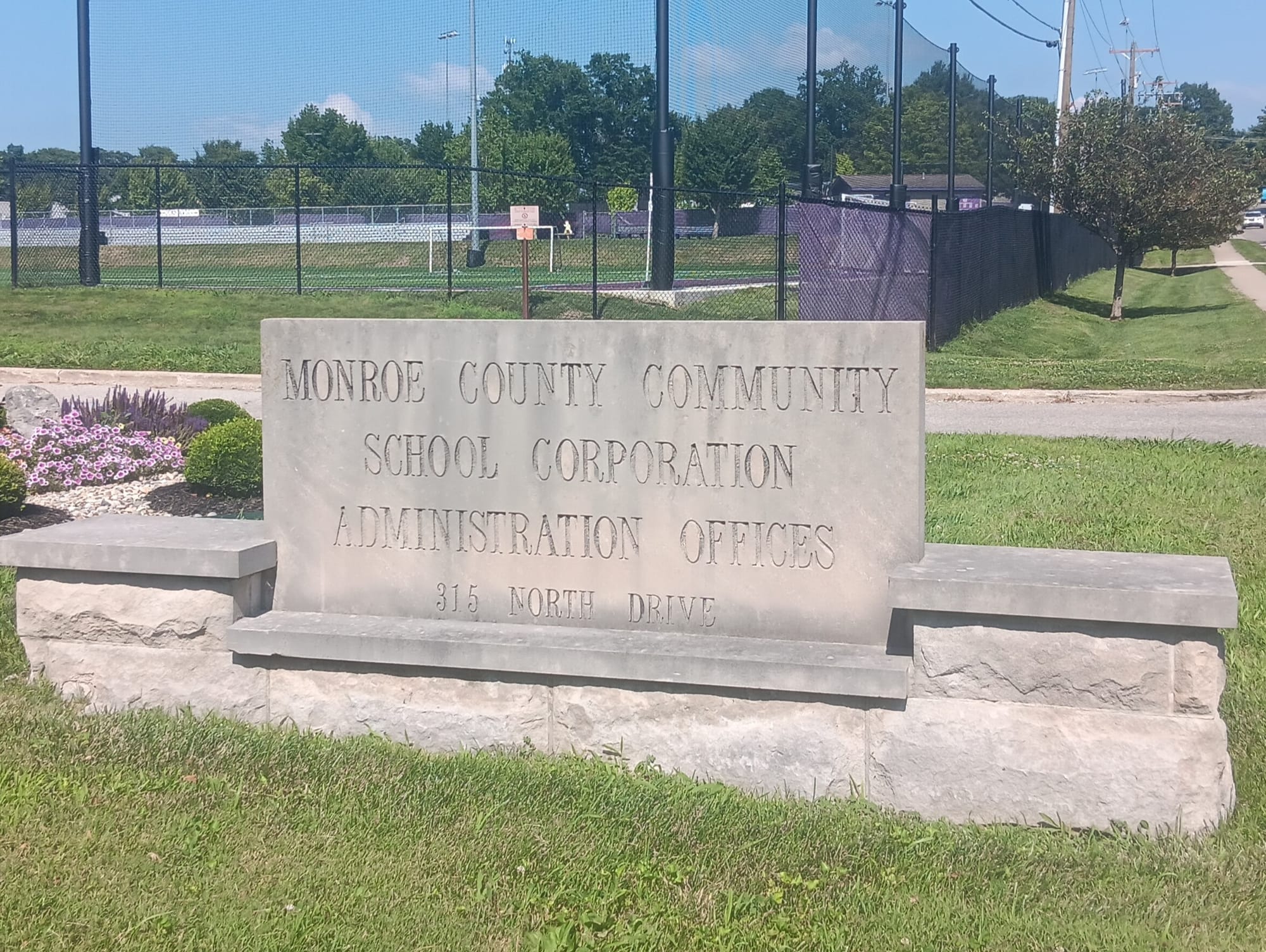 a limestone sign engraved with the words "MONROE COUNTY COMMUNITY SCHOOL CORPORATION ADMINISTRATION OFFICES 315 NORTH DRIVE"