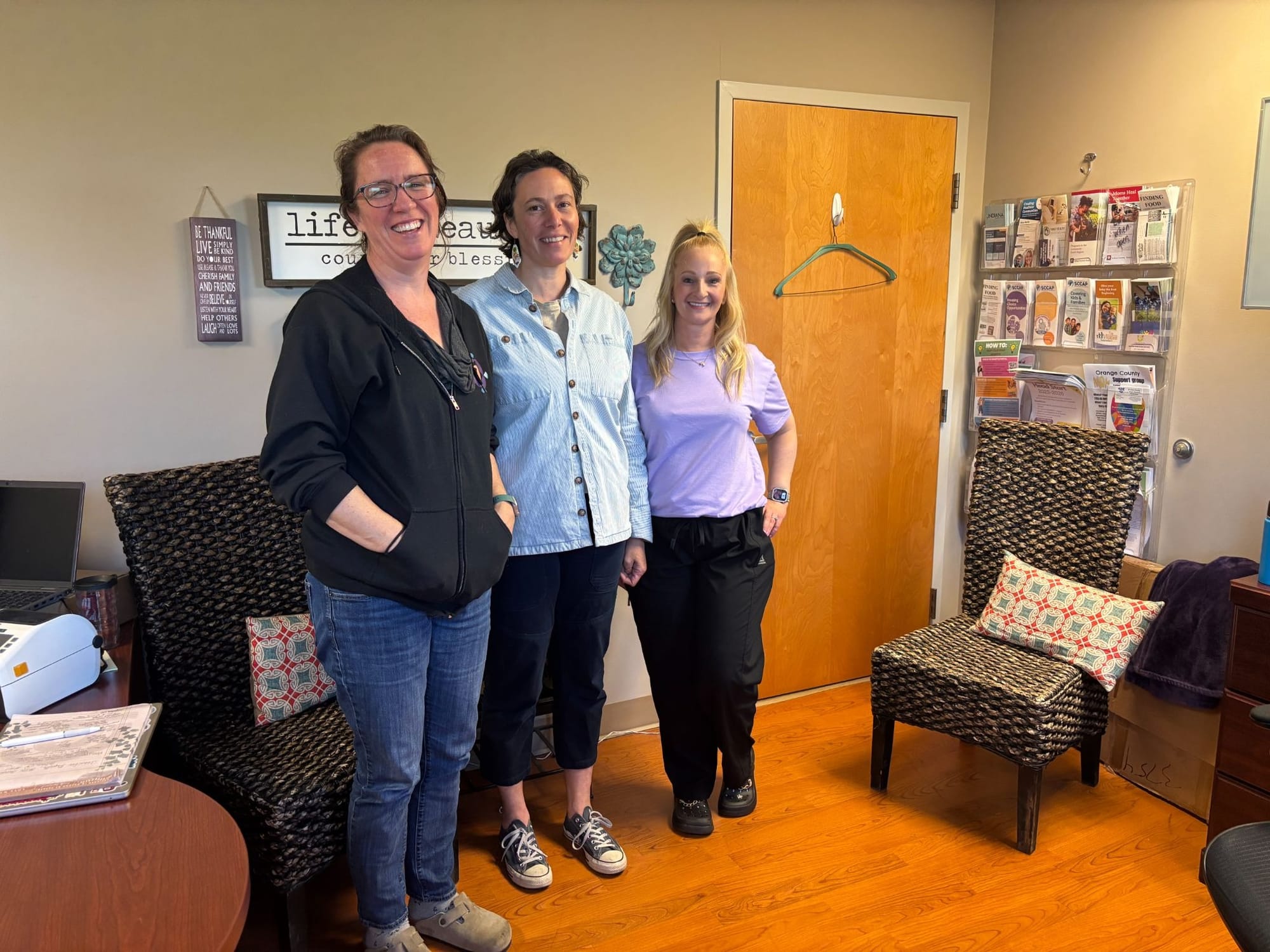 three women stand smiling in a waiting room