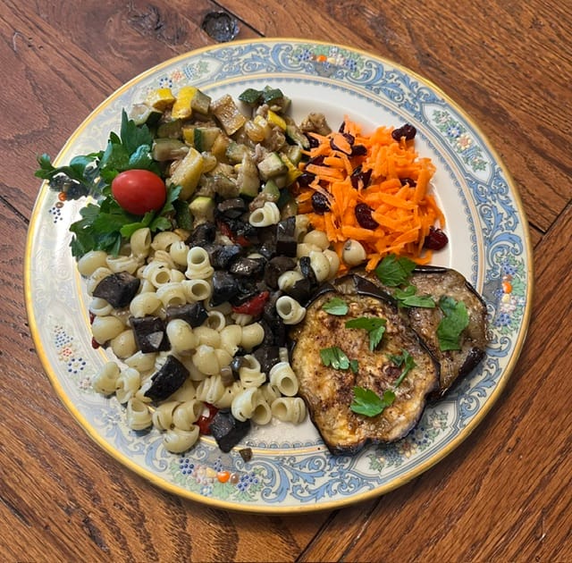a plate laden with mushroom pasta, carrot salad, cook squash, and roasted eggplant