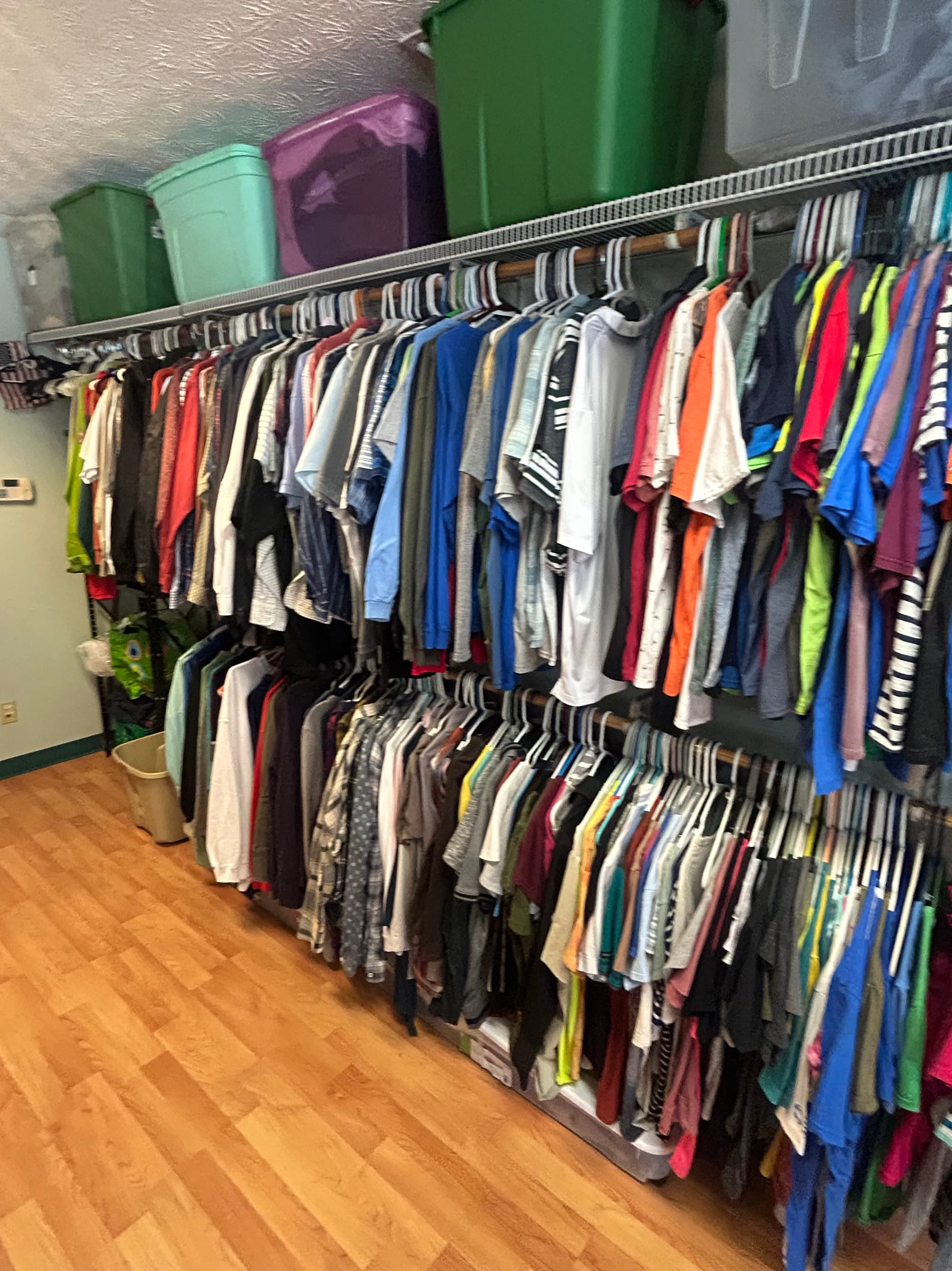 a two-tiered clothing rack with tote boxes on a shelf above