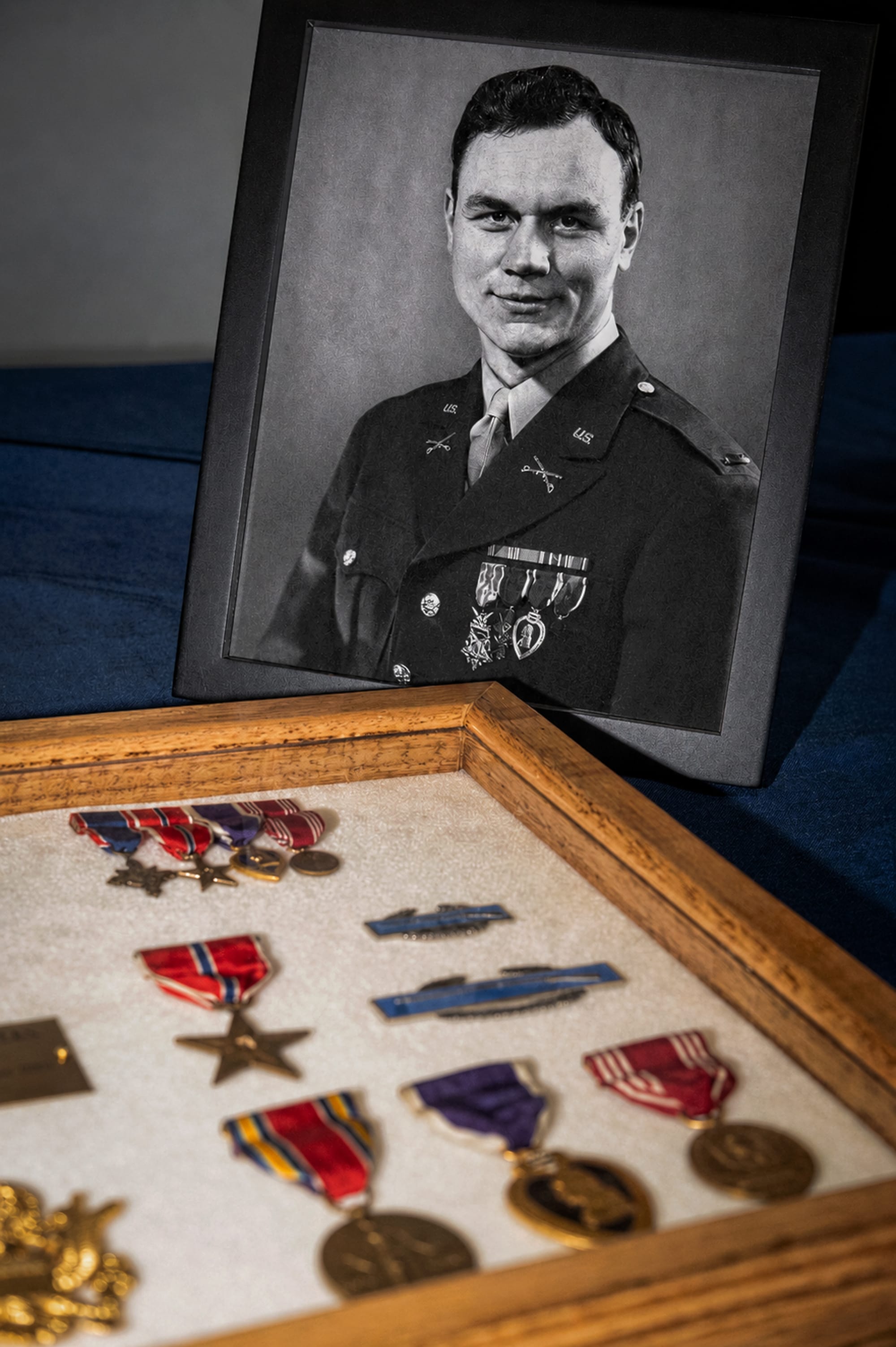 a case displaying various medals in front of a black and white photo of Kisters in military uniform