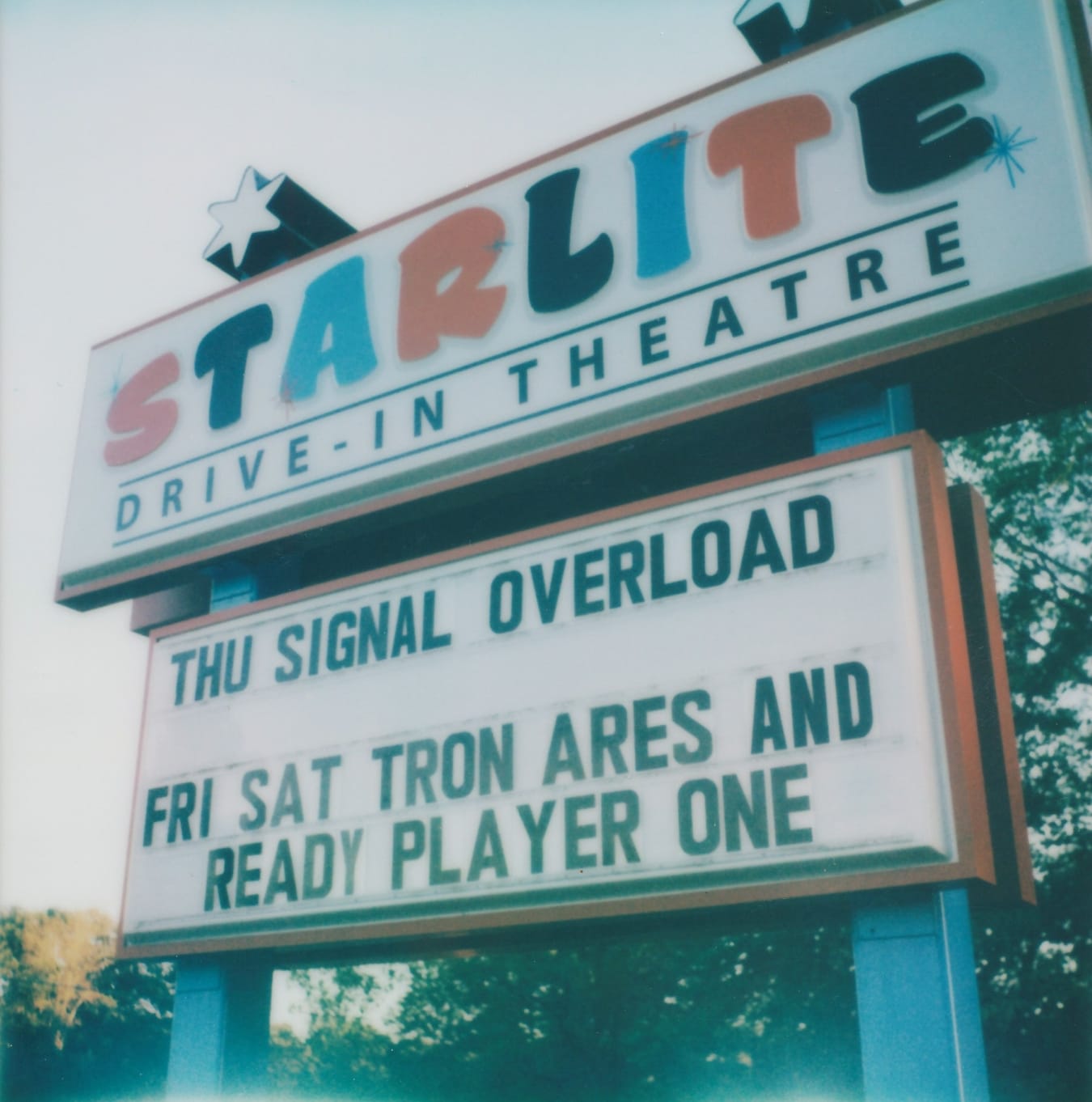 a blue, white, and red marquee sign for Starlite Drive-In Theatre advertising Signal Overload on Thursday and "Tron Ares" and "Ready Player One" on Friday and Saturday