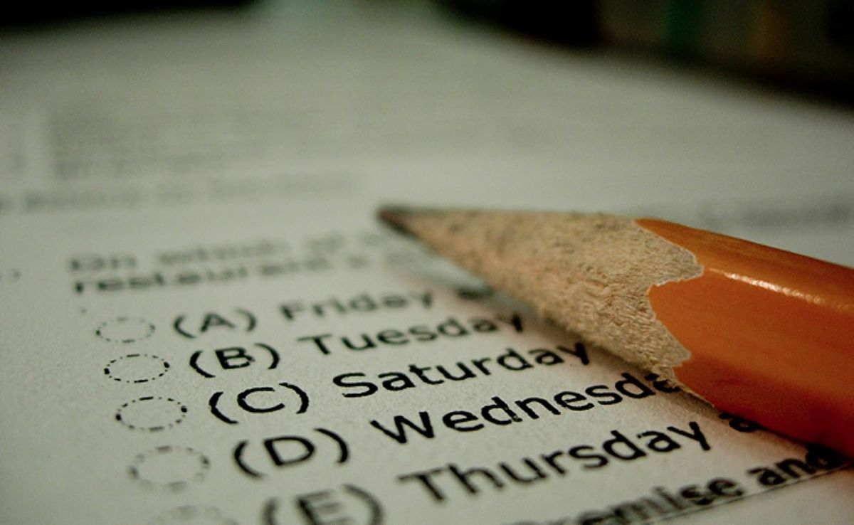 a yellow wooden pencil rests atop a sheet of paper printed with a multiple-choice question, the answers to which are various days of the week