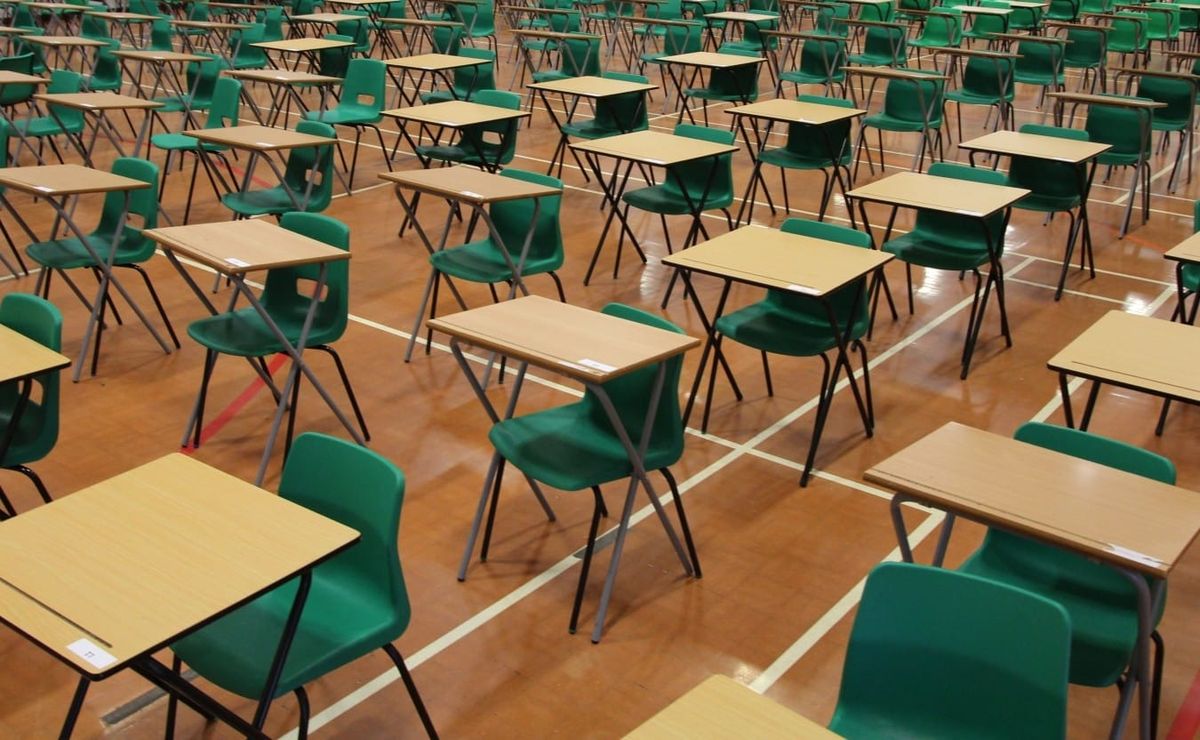 a large room with multiple, even rows of green and brown school desk chairs