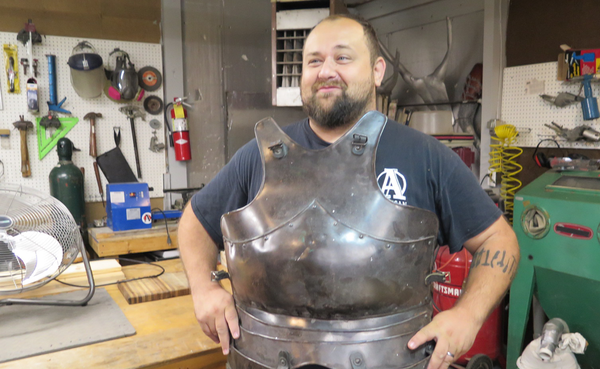 Adam Nahas in Burl and Ingot Tool Library showing a piece of armor that he made. The Tool Library is part of Artisan Alley, t