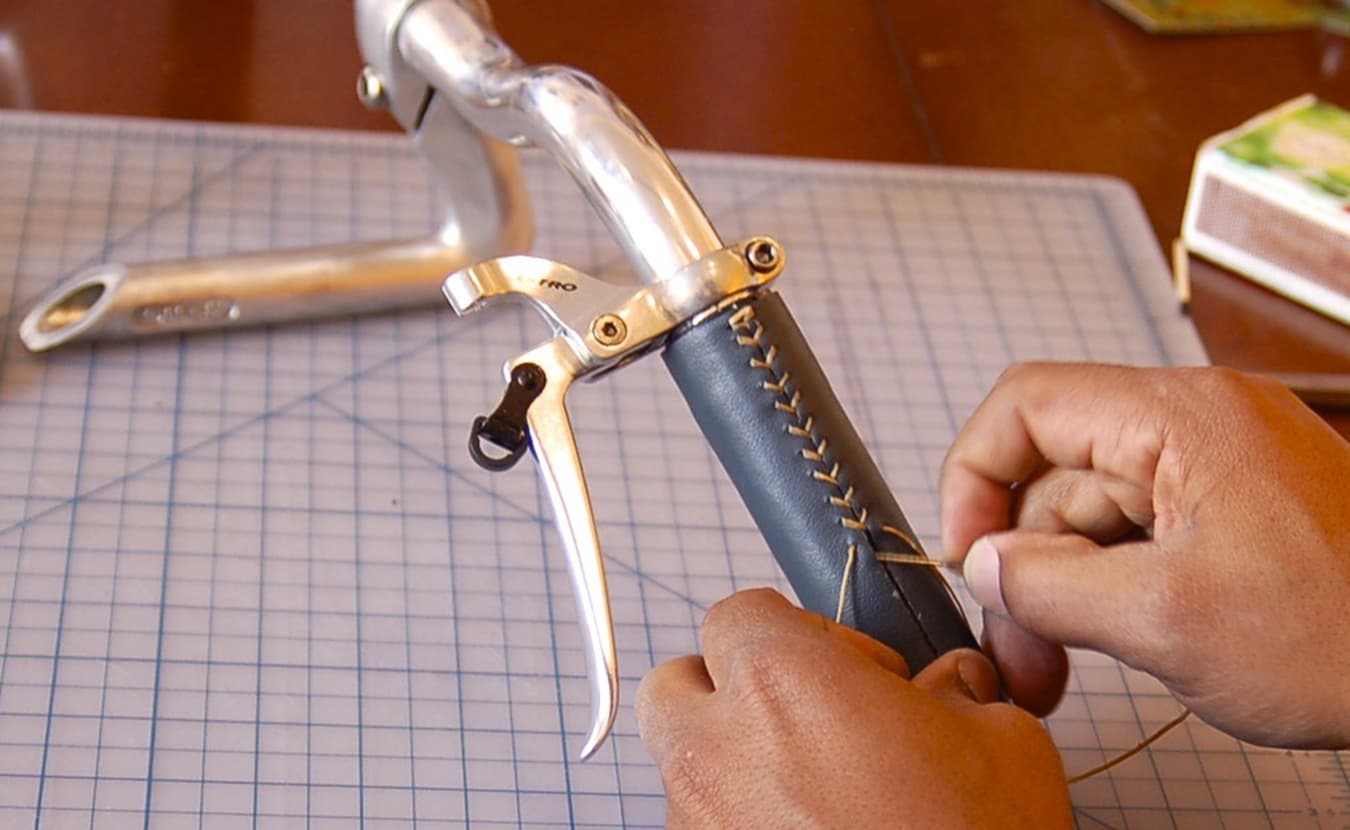 The leather for the handlebar, which was salvaged from an old sofa, is cut to size, carefully perforated with holes along each edge, then sewn together with needle and thread. | Photo by Samuel Sveen
