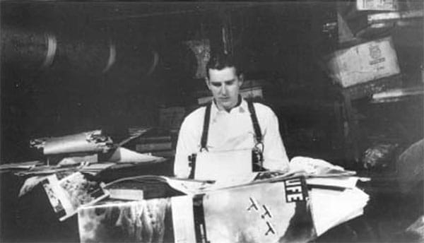 RLJ writes "The Dream of the Flesh of Iron," a 400-page epic poem written from 1939 to 1941, in the basement of his parents' house. He is surrounded by the eclectic sources he worked into this "strange," unpublished work. | Photo by Vernice Baker Lockridge. Photographs from <a href="http://www.raintreecounty.com/bookphot.html" target="_blank">raintreecounty.com</a> are used with permission of The Estate of Ross Lockridge, Jr.