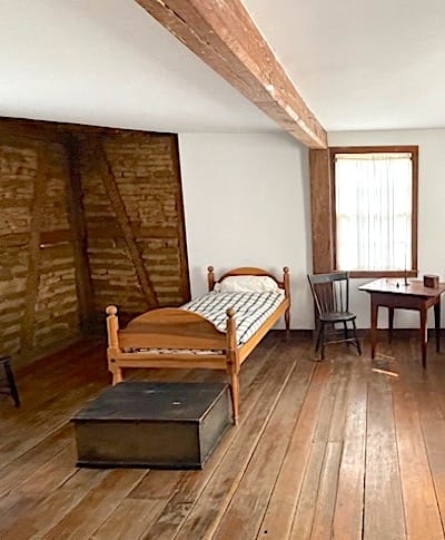 Inside the second floor of the David Lenz House features an exposed wall (left) showing the “Dutch biscuit” construction of wood wrapped with mud and straw. | Photo by Laurie D. Borman