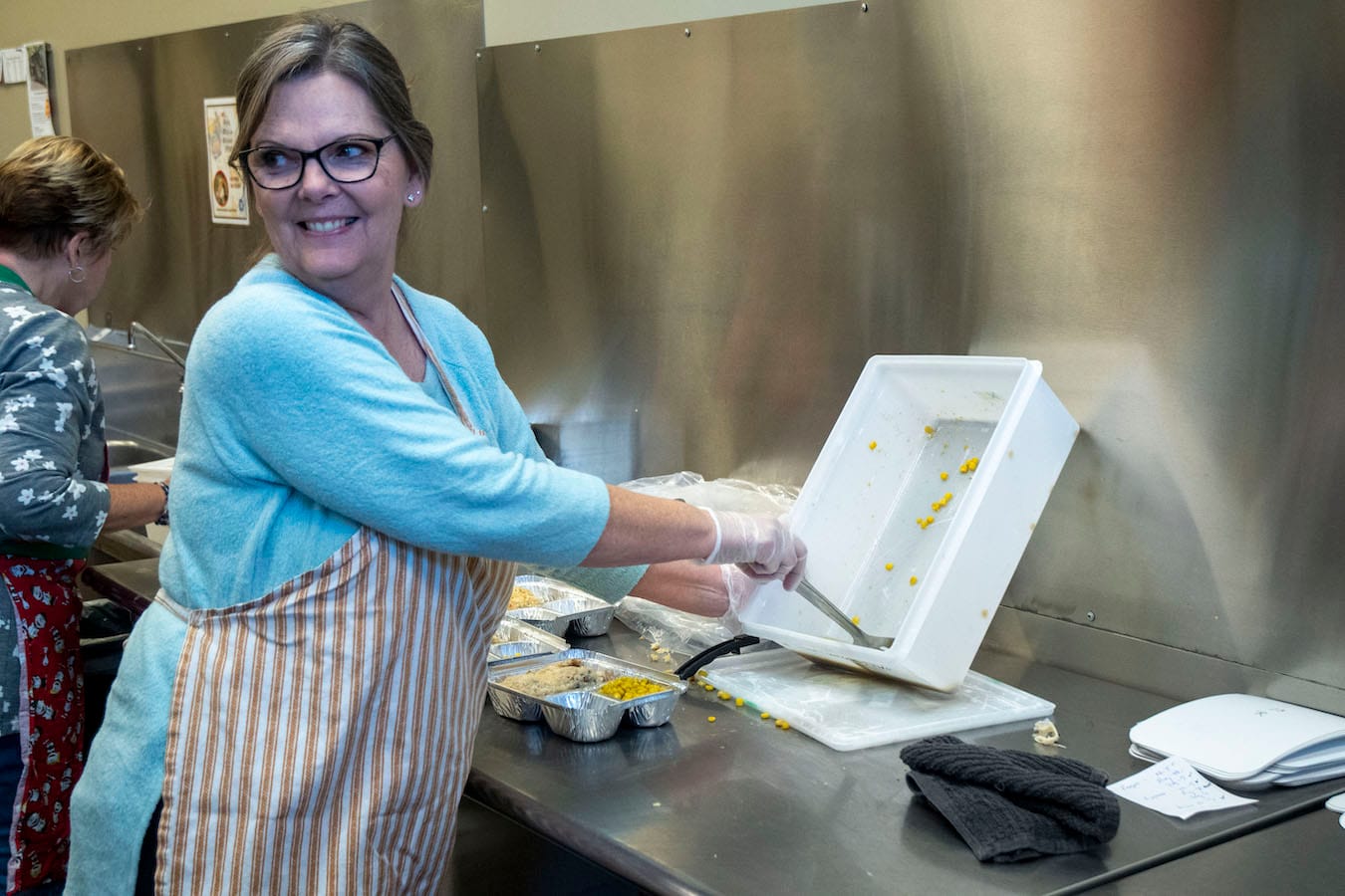 A volunteer fills a take-home meal at Community Kitchen. | Photo by Olivia Bianco