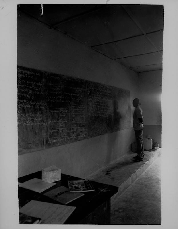 Le Professeur, Kankan, Guinea, 2009, Gelatin Silver Print. A man teaches young children in a small schoolhouse.
