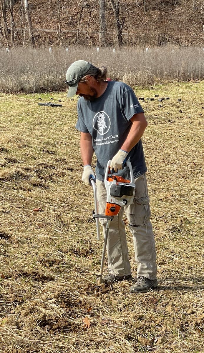 Chris Fox, land stewardship director of Sycamore Land Trust, drilling holes for planting. | Courtesy photo