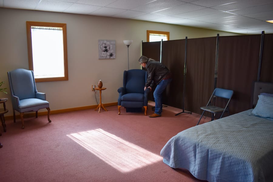 Rick arranges a recliner in the room where the patient will sleep. Grants and donations, like the chair, have sustained the Harmony project. | Photo by Haley Miller