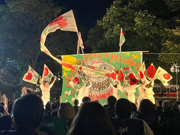 A group of white-clad performers hoist banners of poppies in the colors of the Palestinian flag.