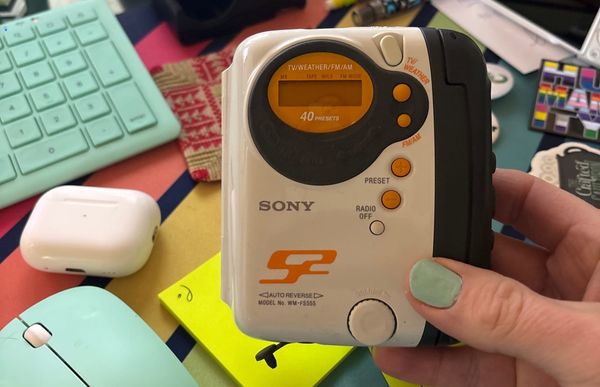 A photo of a vintage 2002 Sony Walkman cassette player that's white, orange, and black.