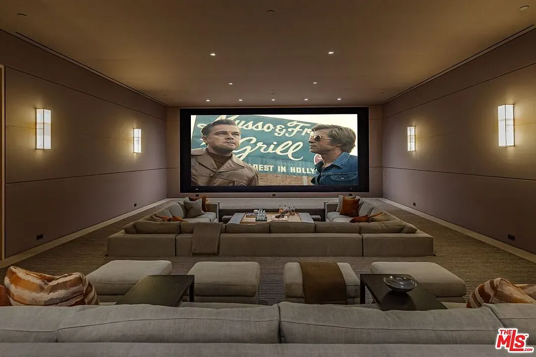 Here's the theater — giant screen, taupe walls, sink-into-it sofas.
