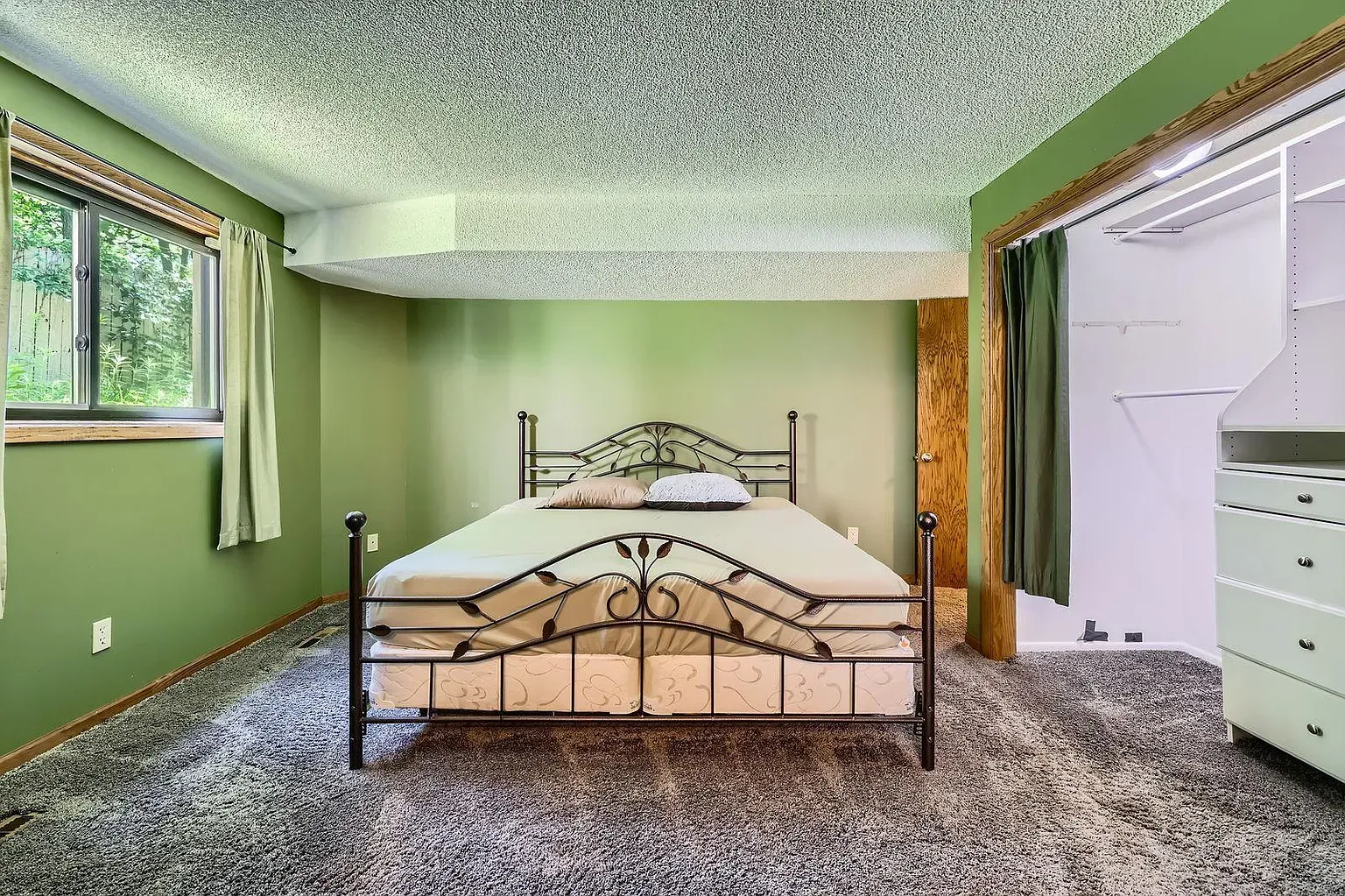 Cozy bedroom—soft green walls, deep gray carpet. Nap mode activated.