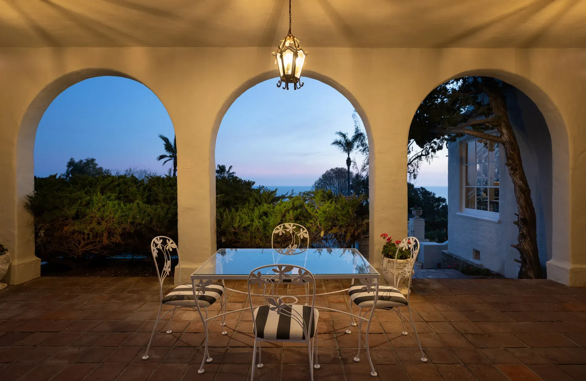 Outdoor dining goals — three arches framing the ocean. Cream walls, lush.