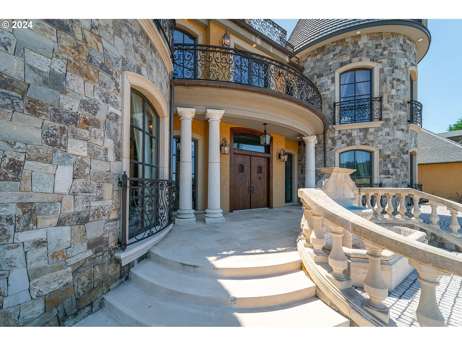 Front facade mixing beige and gray stone. Fancy but not trying too hard.