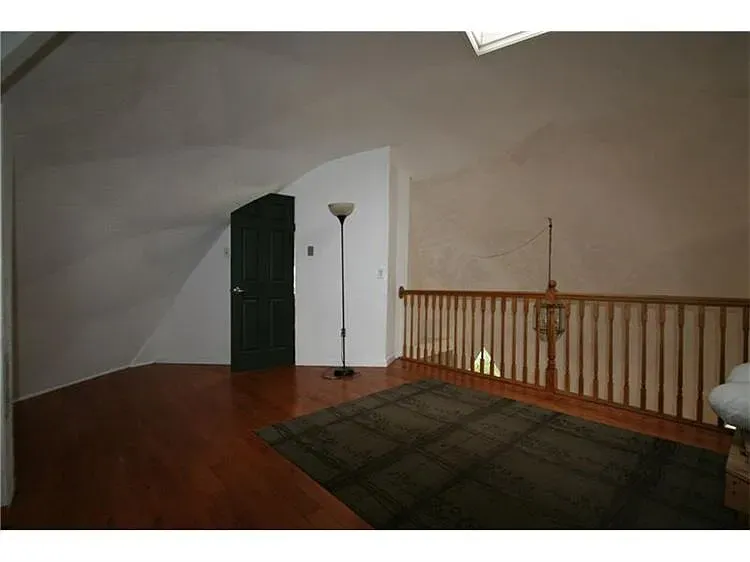 Inside, sloped ceiling feels cozy-but-open. Warm walls, hardwood floor shine. From this angle, taller.