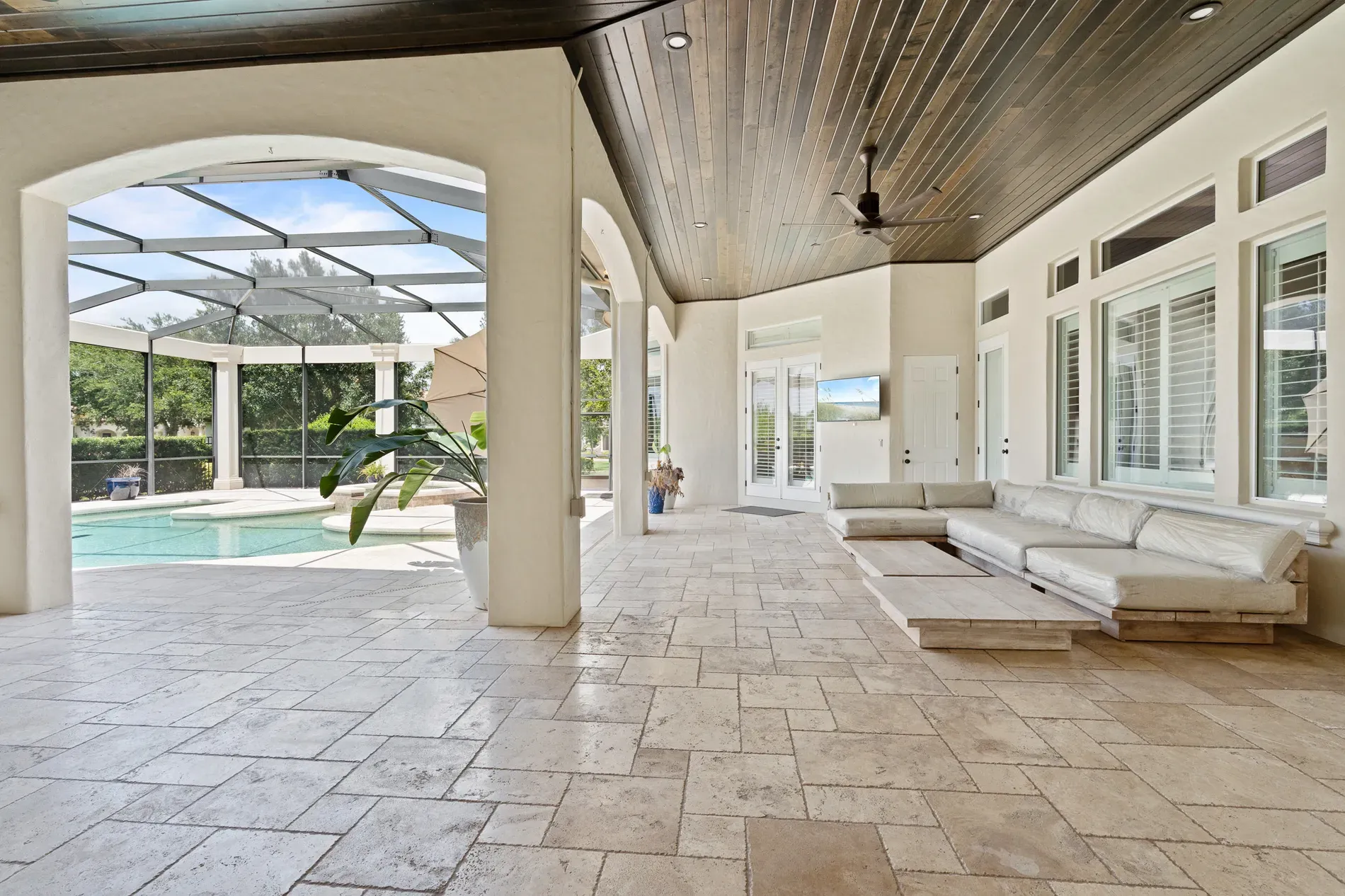 From this angle, screened patio with dark wood ceiling, light stone floor. Breezy.