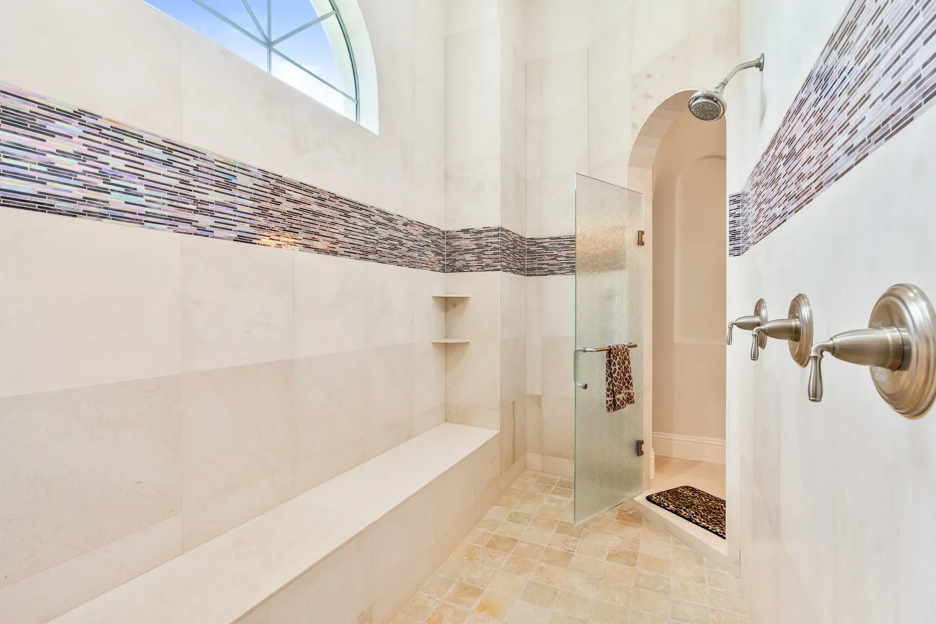 Shower with the arch—cream stone everywhere. Spa vibes achieved.