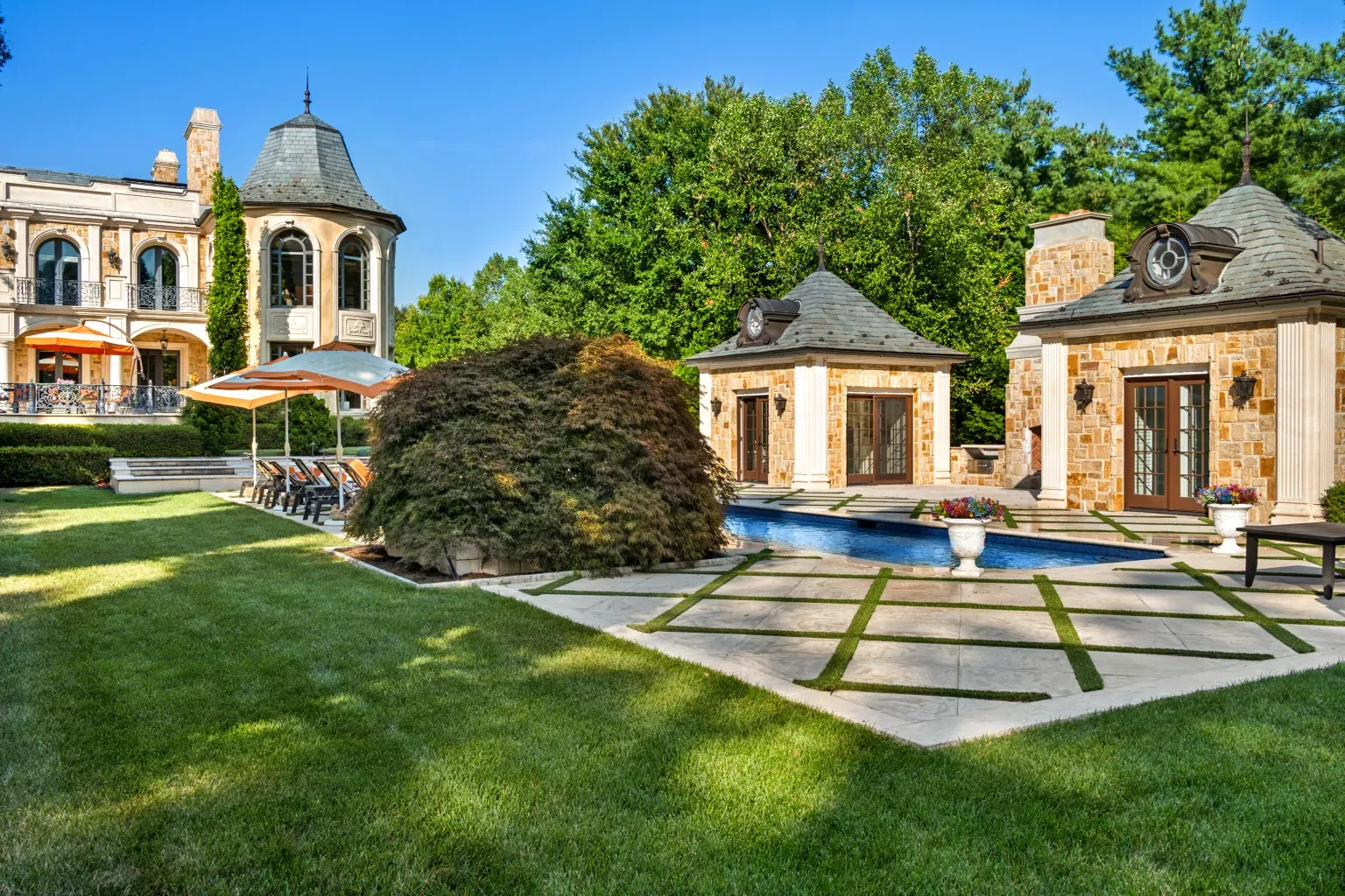 Pool scene—stone outbuildings, slate roofs, lush hedges. Resort vibes.