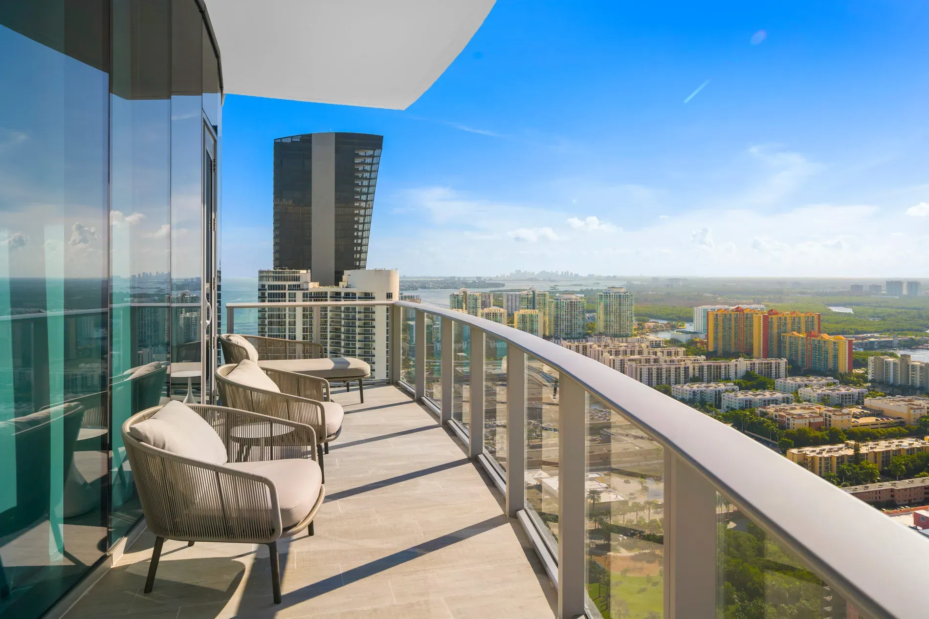 Glass-railed balcony over the city. Chairs say coffee now, emails later.