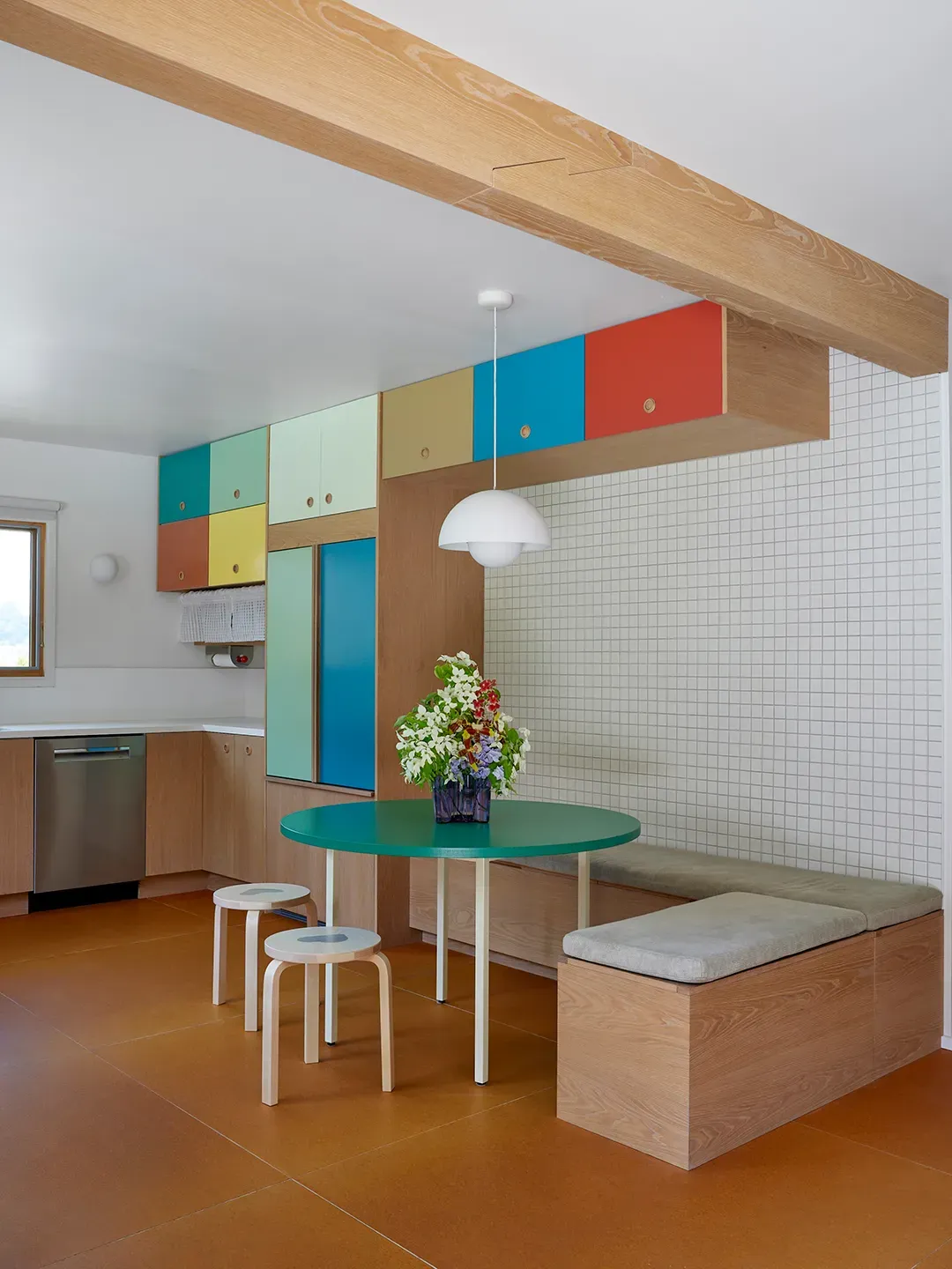 Here's the kitchen-dining — light wood everywhere, pastel cabinets. Mint, orange, blue vibes.