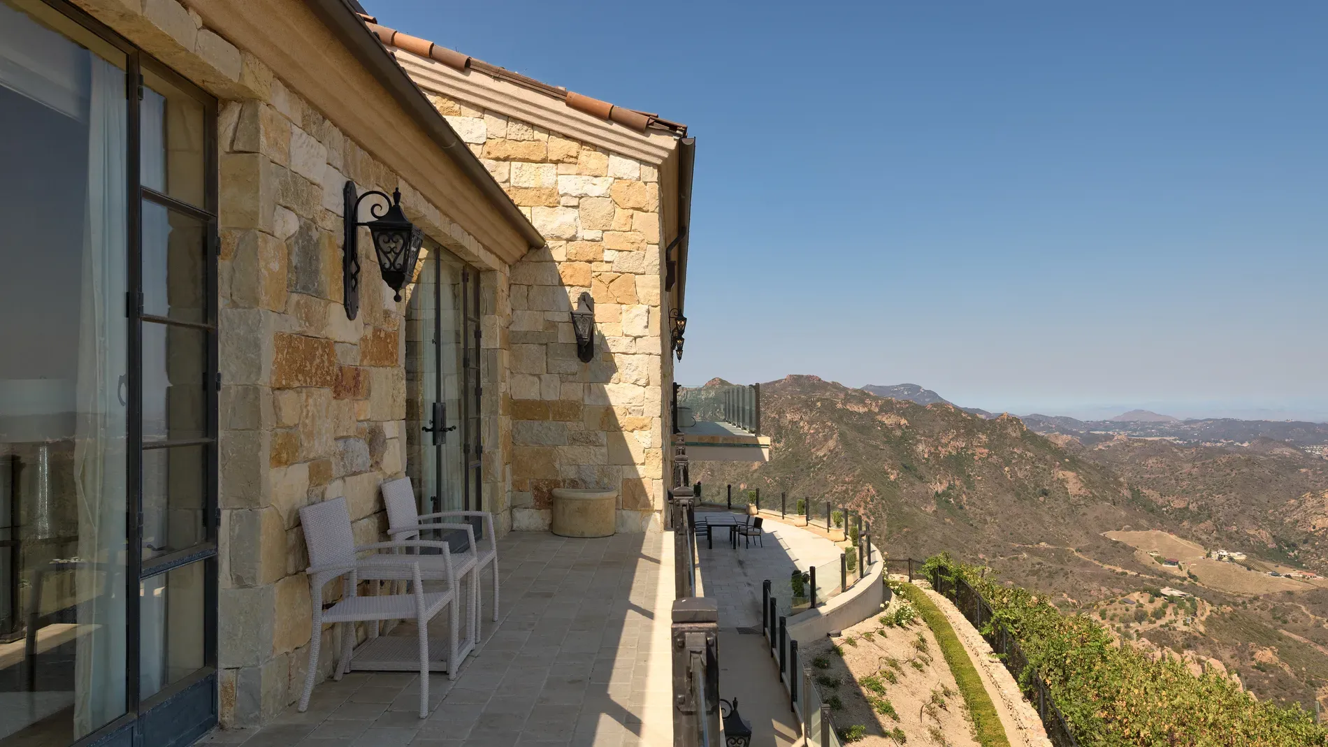 Another terrace—beige and cream stone, full mountain backdrop. Kinda perfect dinner spot.