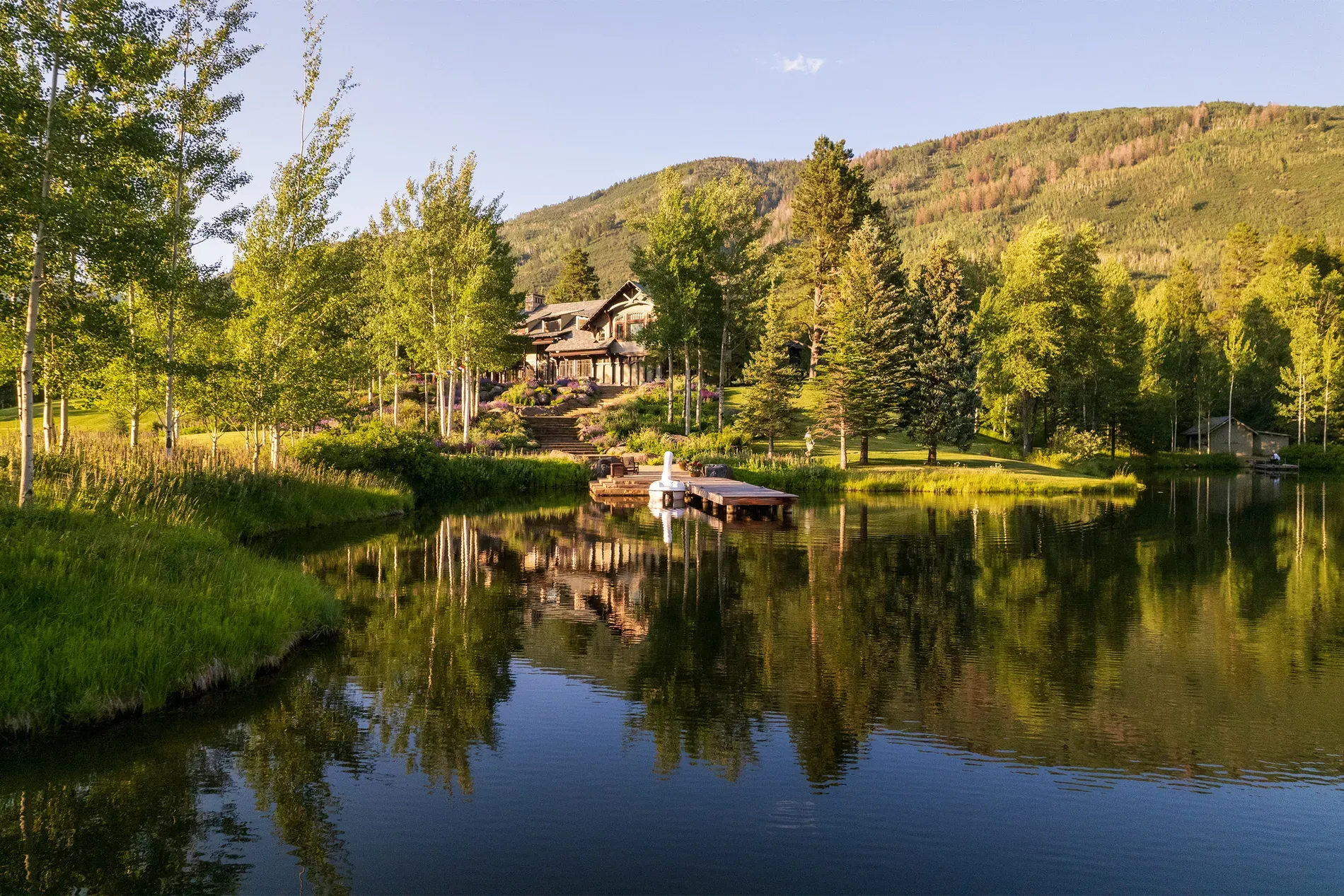 Calm pond scene. Cabin tucked in, huge windows. Feels quiet, almost too perfect.